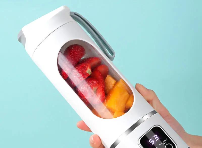 Hand holding a Tumbla Go blender filled with strawberries and mango